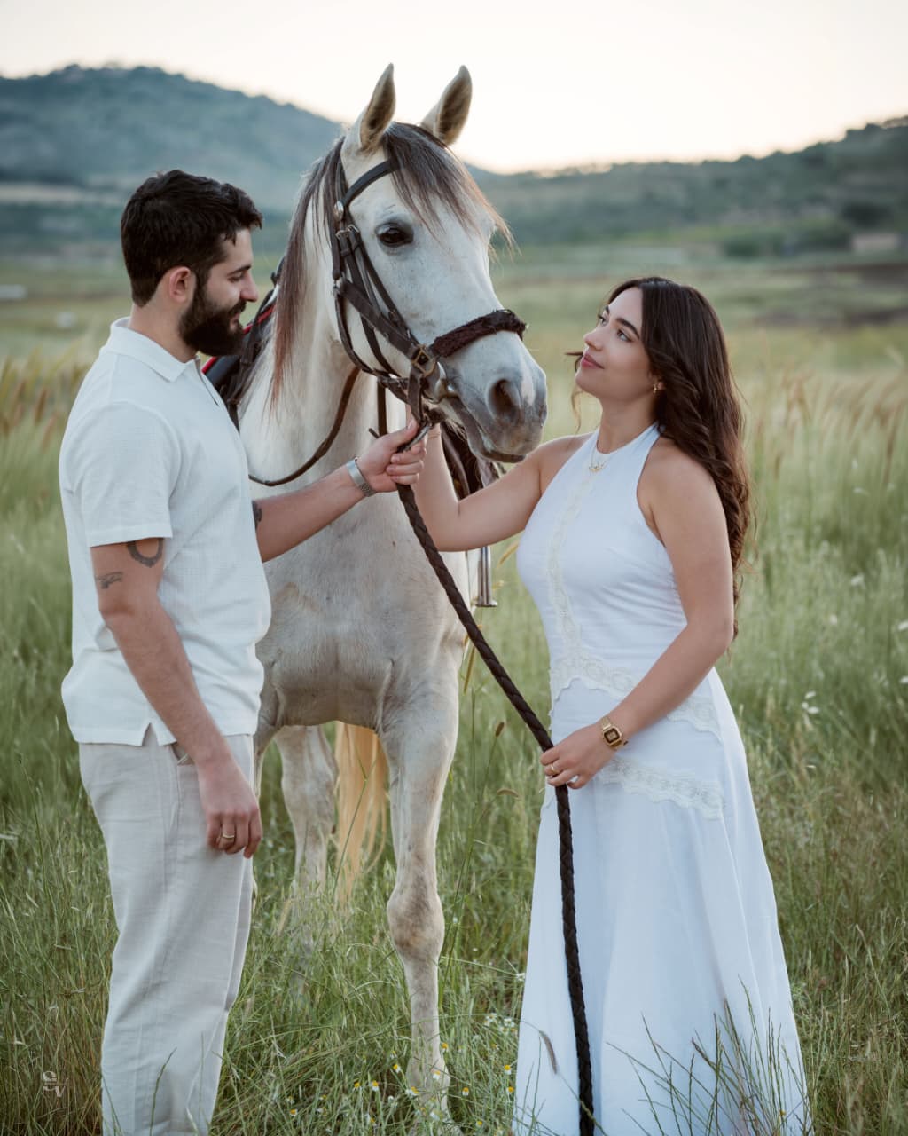 Amir and Lynn standing with a white horse in the field