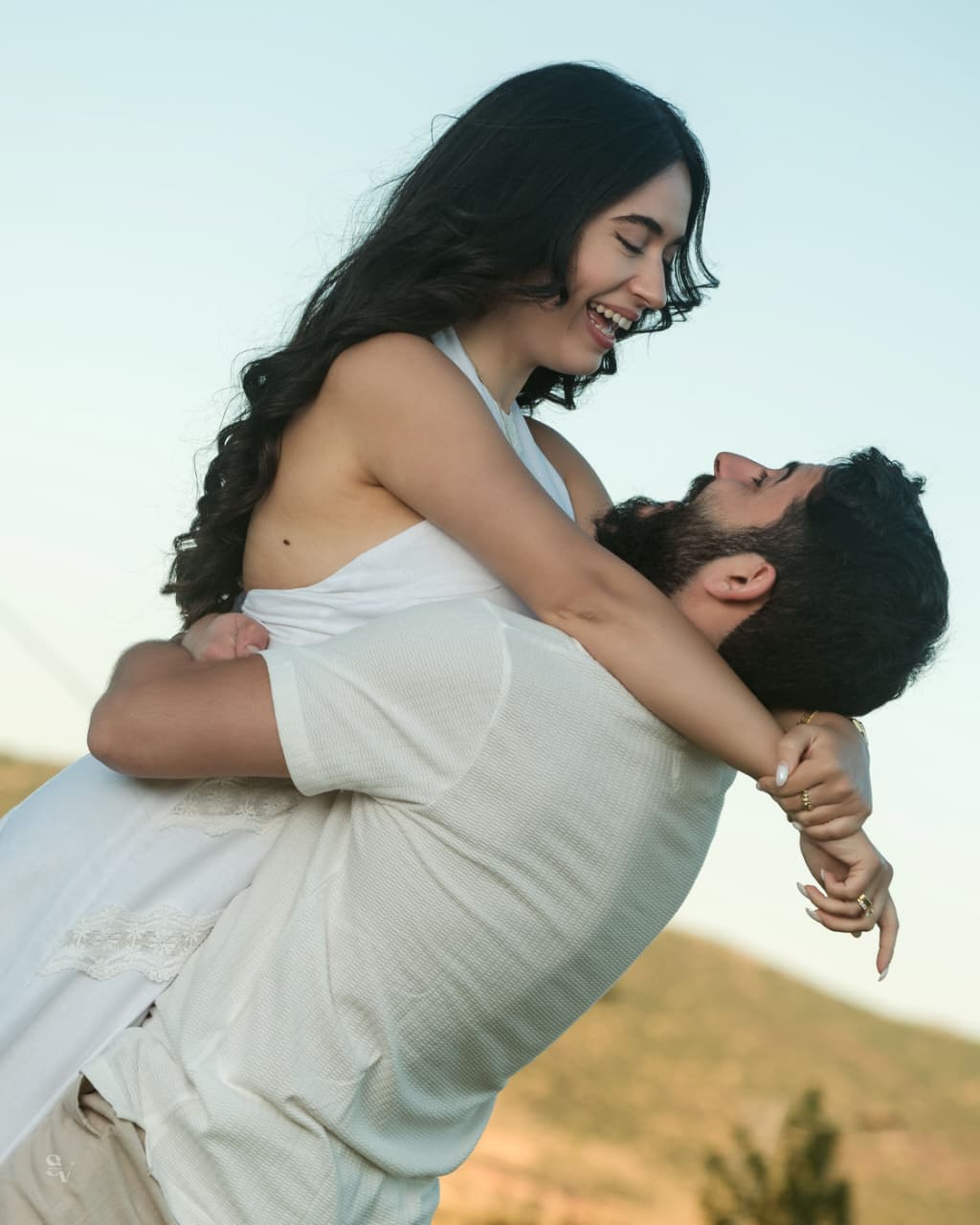 Amir and Lynn smiling in a close lifted embrace