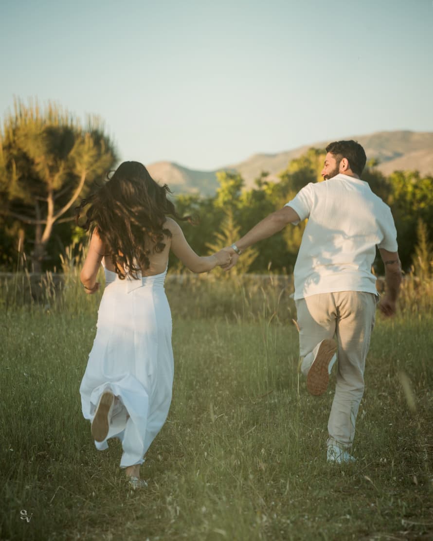 Amir and Lynn running hand in hand through a field