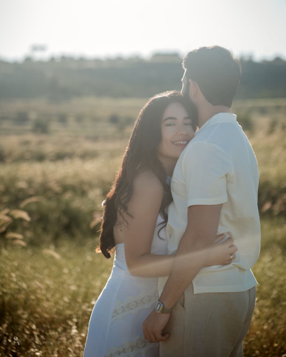 Amir and Lynn sharing a sunlit embrace in the field